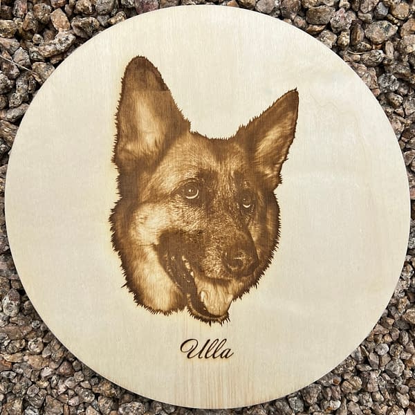Cute white German shepherd portrait with name Ulla Laser engraved on Poplar Wood Circle lying on rocks.