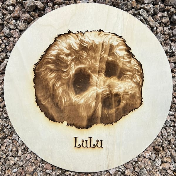 Cute fluffy white lapdog portrait I with name Lulu Laser engraved on Poplar Wood Circle lying on rocks.